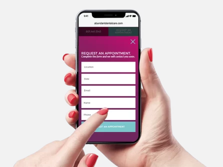Person Holding Mobile Device And Filling Out Abundant Dental Care Contact Form On Website